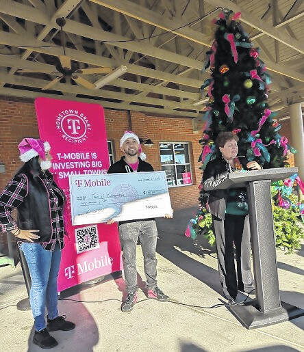 <p>Terri Dennison addresses the crowd as Irra and DeTre gleam behind her.</p>