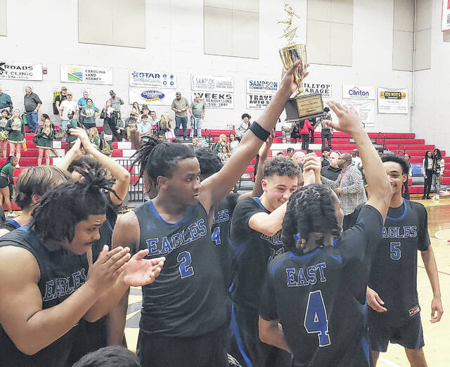 Keyshawn Kemp holds up the Carolina Conference tournament championship trophy as East Bladen teammates celebrate Friday.
                                 Sonny Jones / Bladen Journal