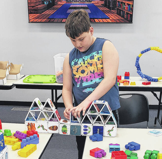 Corbin Norris puts the finishing touches on his bridge-building challenge during Hangout Hub.
                                 Sonny Jones / Bladen Journal
