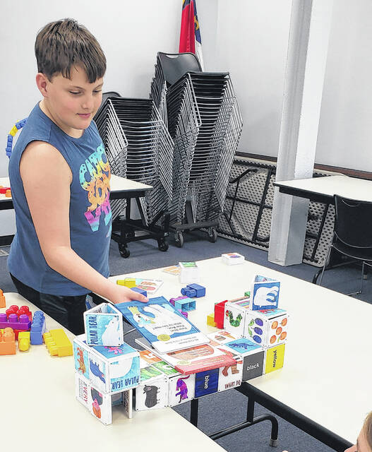 Corbin Norris places books on top of the bridge built by his father, Brent Norris.
                                 Sonny Jones / Bladen Journal