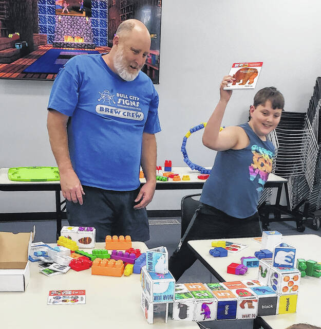 Brent Norris, left, watches as his son, Corbin Norris, prepares to place a book atop a bridge that Brent constructed.
                                 Sonny Jones / Bladen Journal