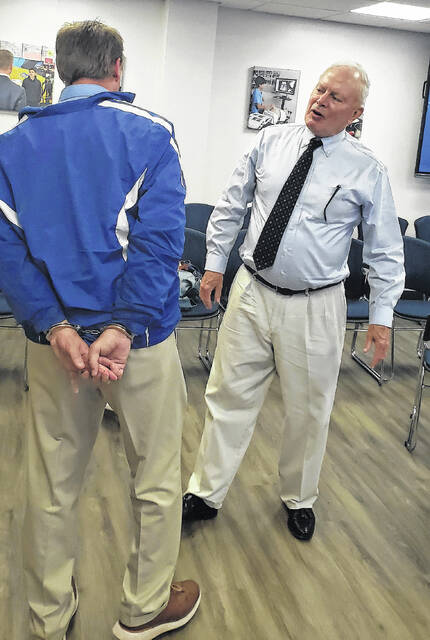 Bladen County Educational Foundation treasurer David Wall (right) talks with East Bladen principal Chris Carroll, who arrived at the Bladen County Board of Education with his hands cuffed behind his back during the Jail-A-Thon held Thursday, April 23.
                                 Sonny Jones / Bladen Journal