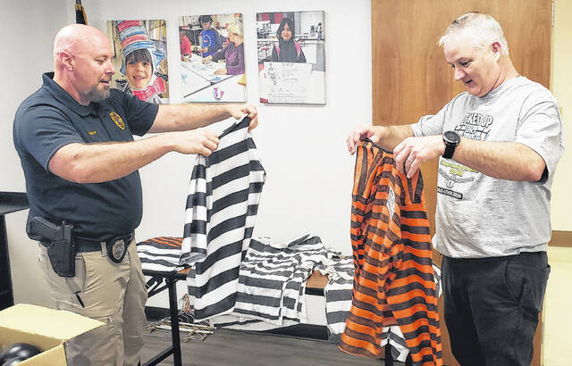 White Lake Police Chief Bruce Smith (left) and Elizabethtown Primarys Chris Cherry look for a prison shirt for Cherry after his arrest during the Jail-A-Thon on Thursday, April 23.
                                 Sonny Jones / Bladen Journal