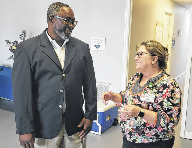 My Treasured Memories owner Carl Carter talks with Elizabethtown-White Lake Chamber of Commerce president Jeané Pope during a grand opening ceremony Friday, April 24.
                                 Sonny Jones / Bladen Journal