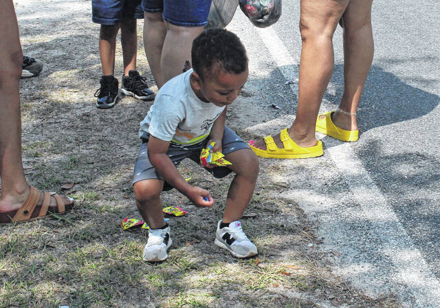 A child picks up candy tossed by several parade entrants.
                                 Sonny Jones / Bladen Journal